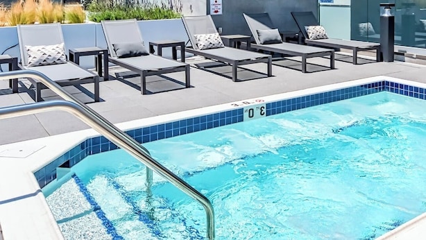 Une piscine avec des chaises longues et une terrasse carrelée.