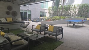 Un espace extérieur aménagé avec des canapés, des chaises et une table de ping-pong.
