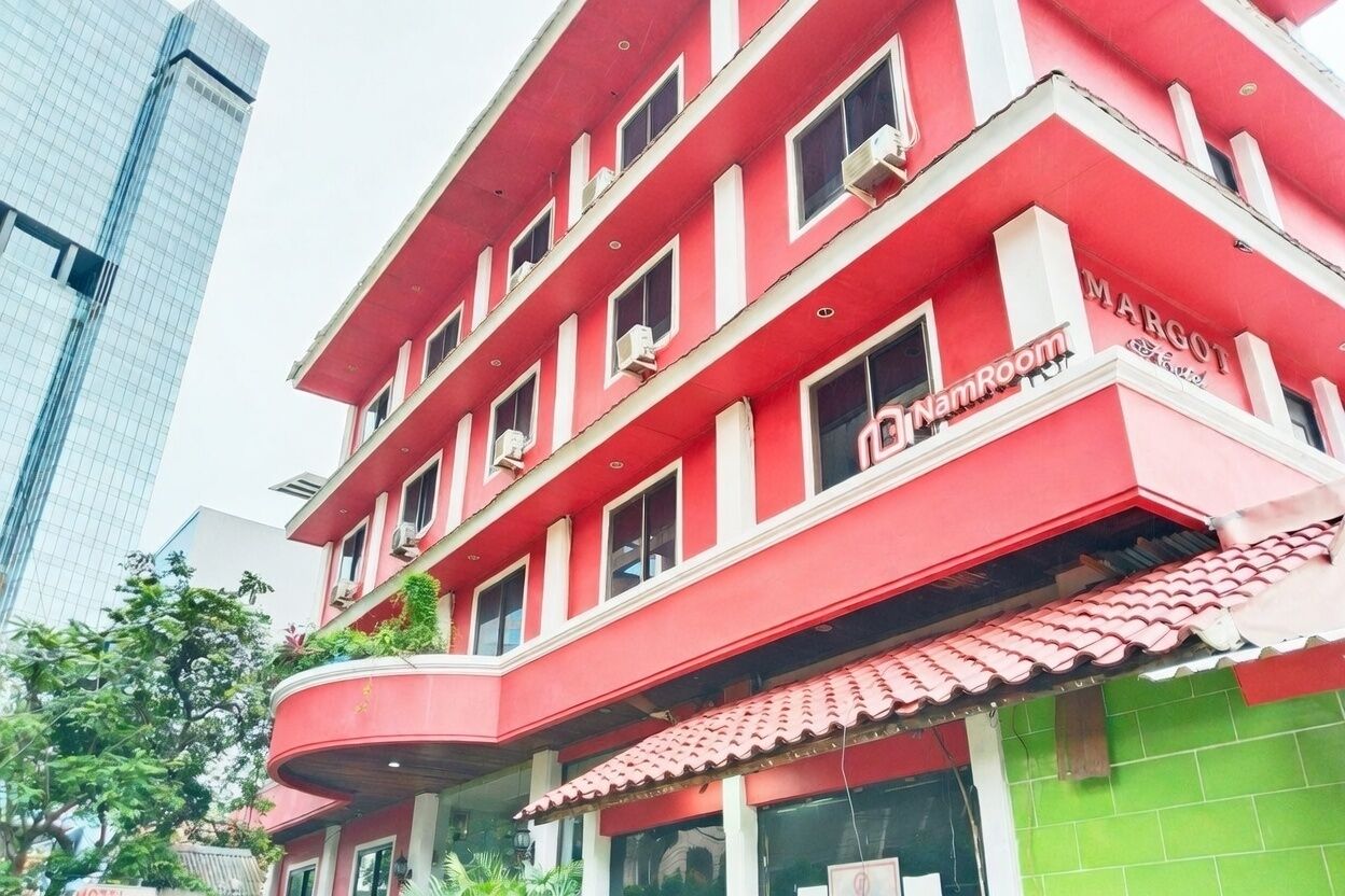Un edificio de varios pisos con fachada roja y un letrero que dice 'JinNamRoom'.