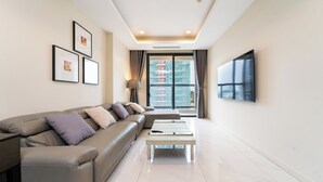 A modern living room with a sofa, a coffee table, and a flat-screen TV mounted on the wall. - The Collection Madison Tower (Ho Chi Minh City)