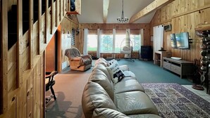 A cozy cabin interior with a wooden interior, a sofa, a television, and a ceiling fan.