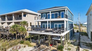 A beachfront property with a two-story building, a covered deck, and outdoor seating. - The Drift Away (Navarre Beach)