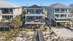 A beachfront property with multiple levels, outdoor seating, and a wooden deck. - The Drift Away (Navarre Beach)