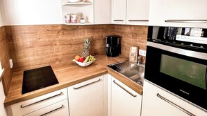 A compact kitchen with white cabinets, a wooden countertop, a built-in microwave, and a coffee maker. - Apartment Balsberg southwest with 2 bedrooms and large balcony with mountain view (Unterwössen)