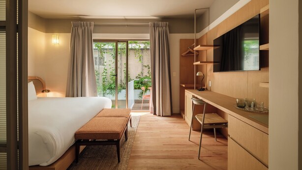 Una habitación de hotel moderna con una cama grande, un escritorio y un televisor.