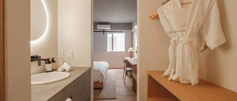 A modern bathroom with a round mirror, a sink, and a robe hanging on a rack.
