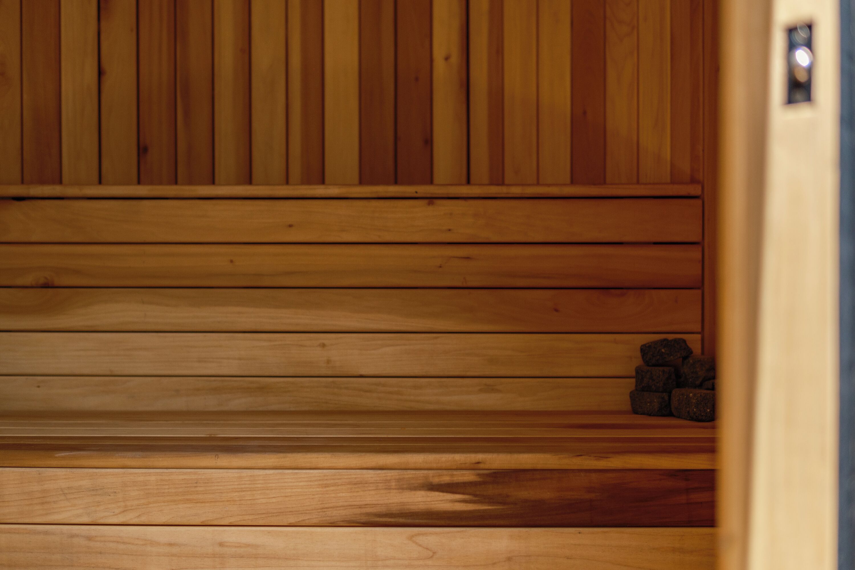 A wooden sauna with benches and stones.