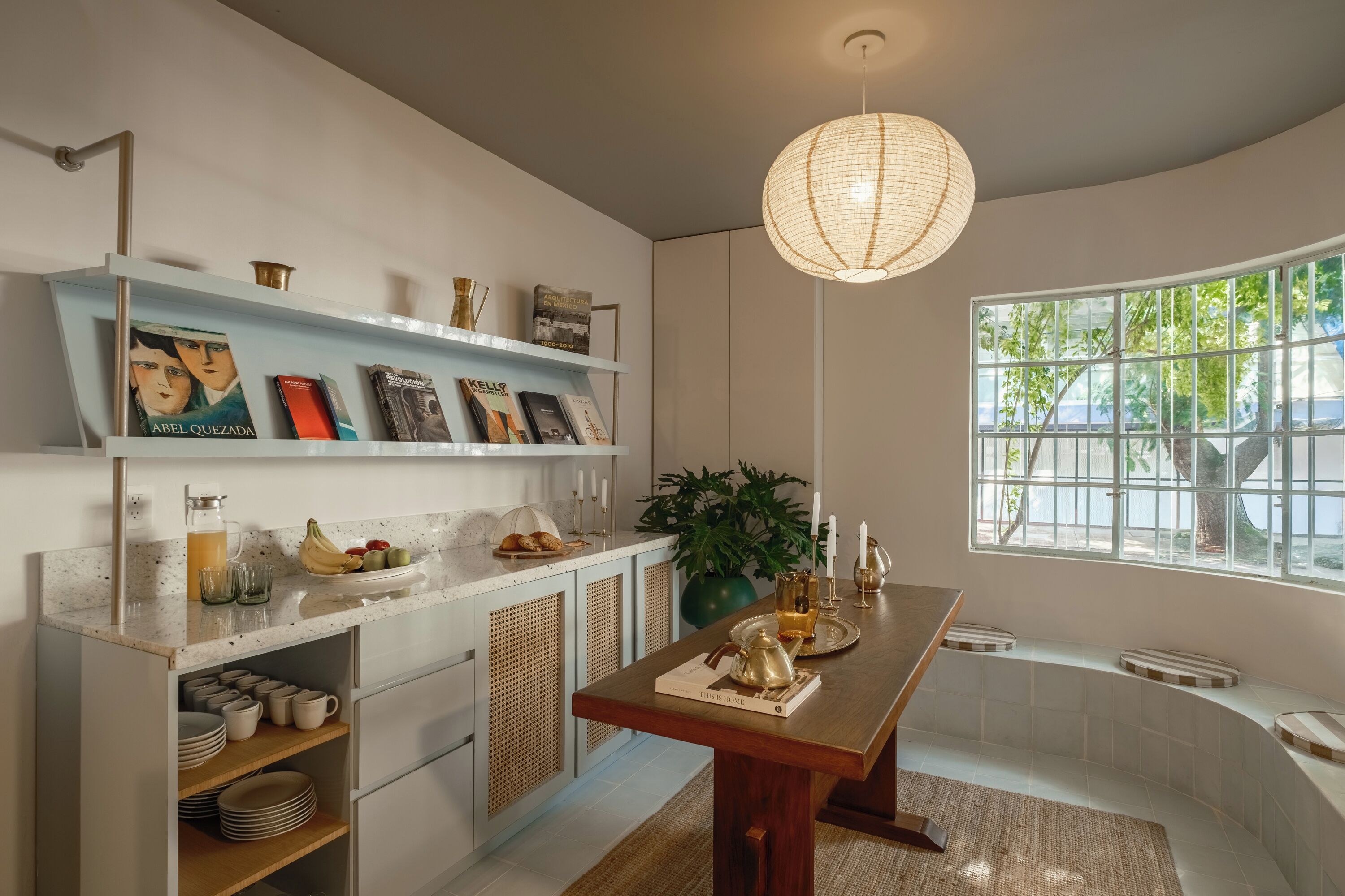Una cocina moderna con una mesa de madera, una lámpara colgante y una ventana con vistas a zonas verdes.