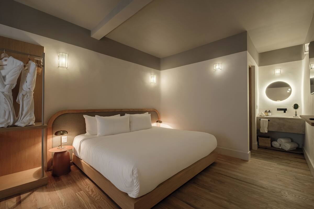 A modern bedroom with a large bed, bedside lamps, a wooden headboard, and a built-in wardrobe.