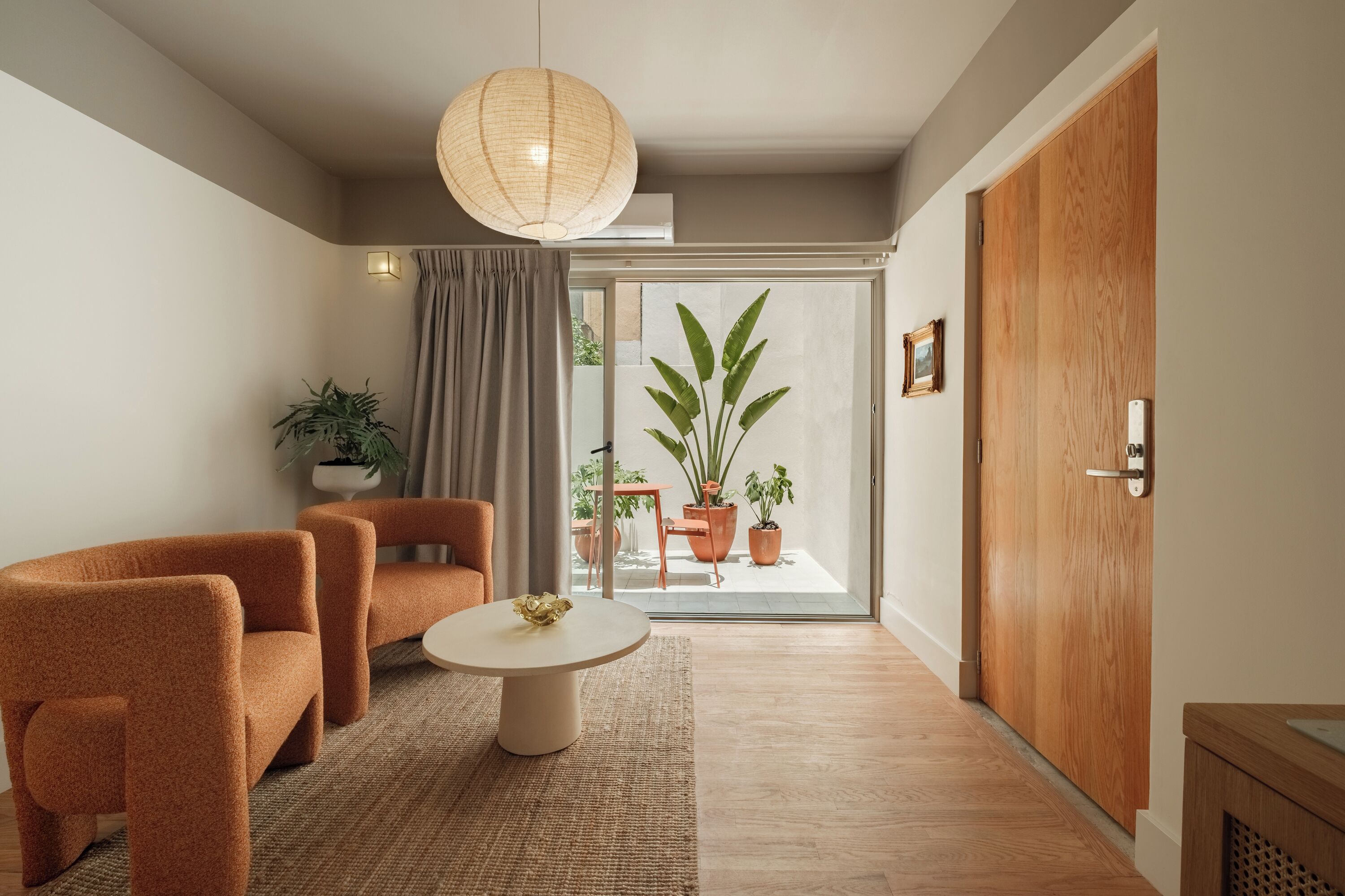 A modern living room with a sofa, a coffee table, and a large window with a view of the outdoors.