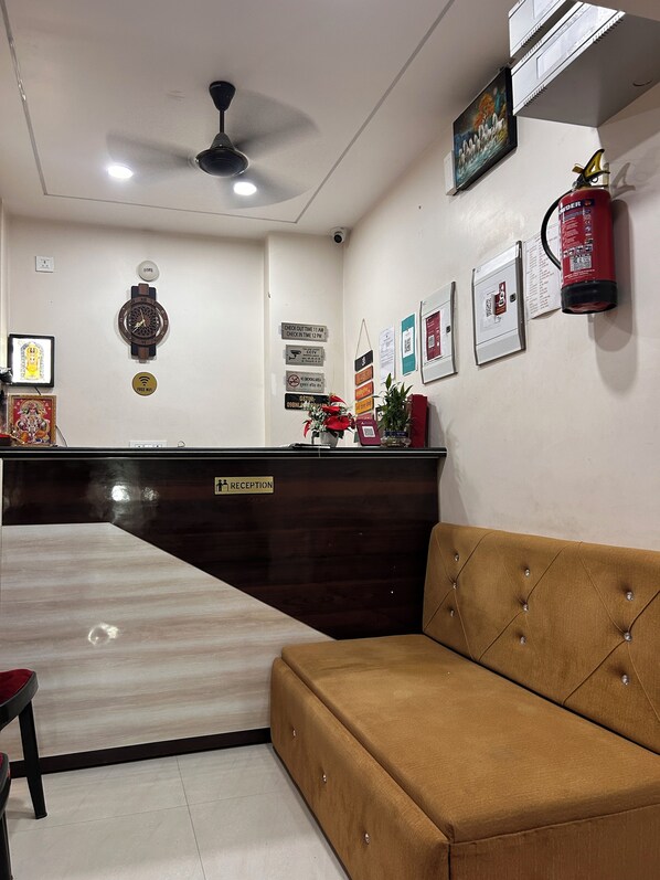 A reception area with a reception desk, a brown sofa, a ceiling fan, and various signs and decorations on the walls. - Swimming Pool Hotel G resort Near temple (Puri)