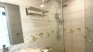 A modern bathroom with a glass-enclosed shower, a white sink, and a toilet. - Mây House Grandworld on the beach (Phu Quoc)