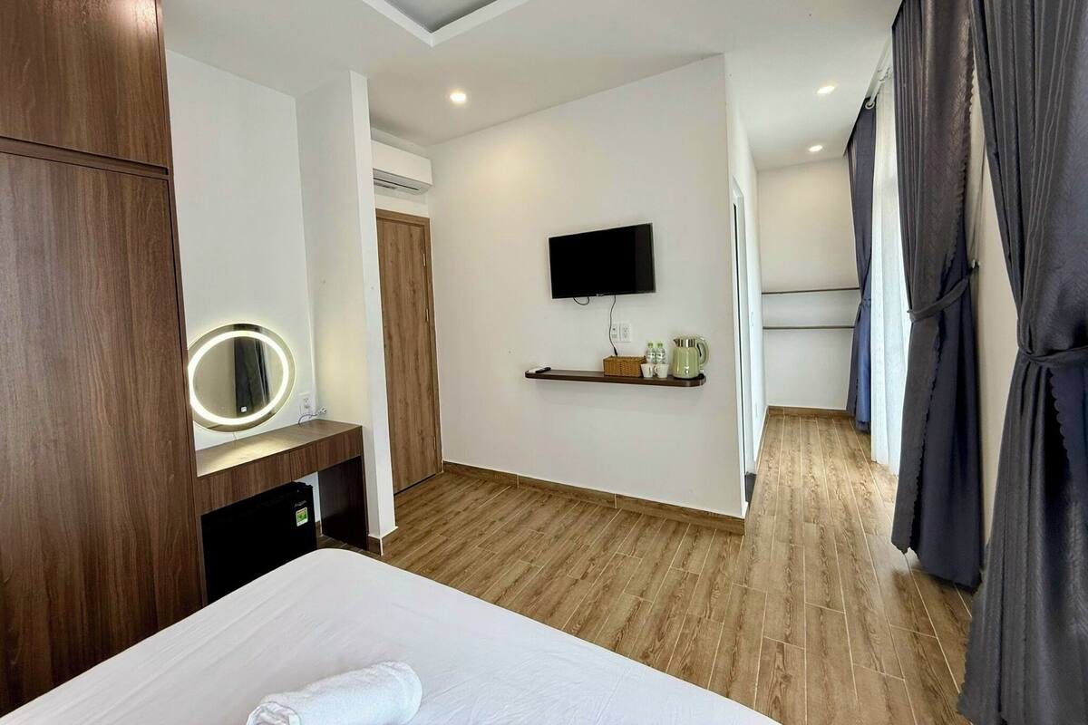 Een hotelkamer met een bed, een kaptafel met spiegel, een aan de muur bevestigde televisie en een plank met toiletartikelen.