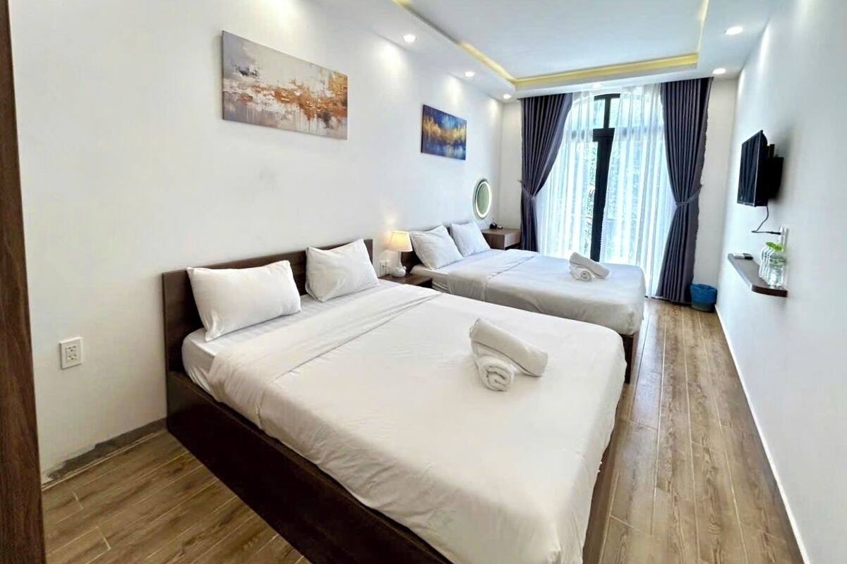 Een hotelkamer met twee bedden, een flatscreen televisie, een klein tafeltje en kunstwerken aan de muur.
