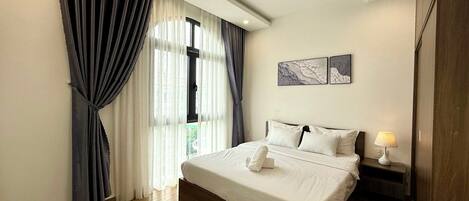 A modern bedroom with a large bed, wooden flooring, and a window with curtains.