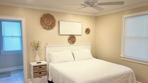 A bedroom with a bed, a nightstand, a vase with a plant, and decorative wall art.