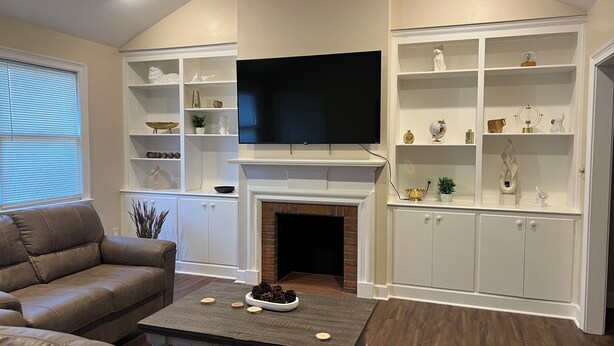 A living room with a fireplace, a flat-screen TV, and built-in shelving with decorative items.