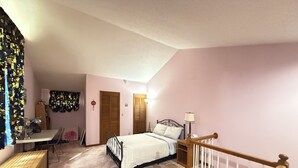 A bedroom with a bed, a desk, a chair, a wardrobe, and a staircase.