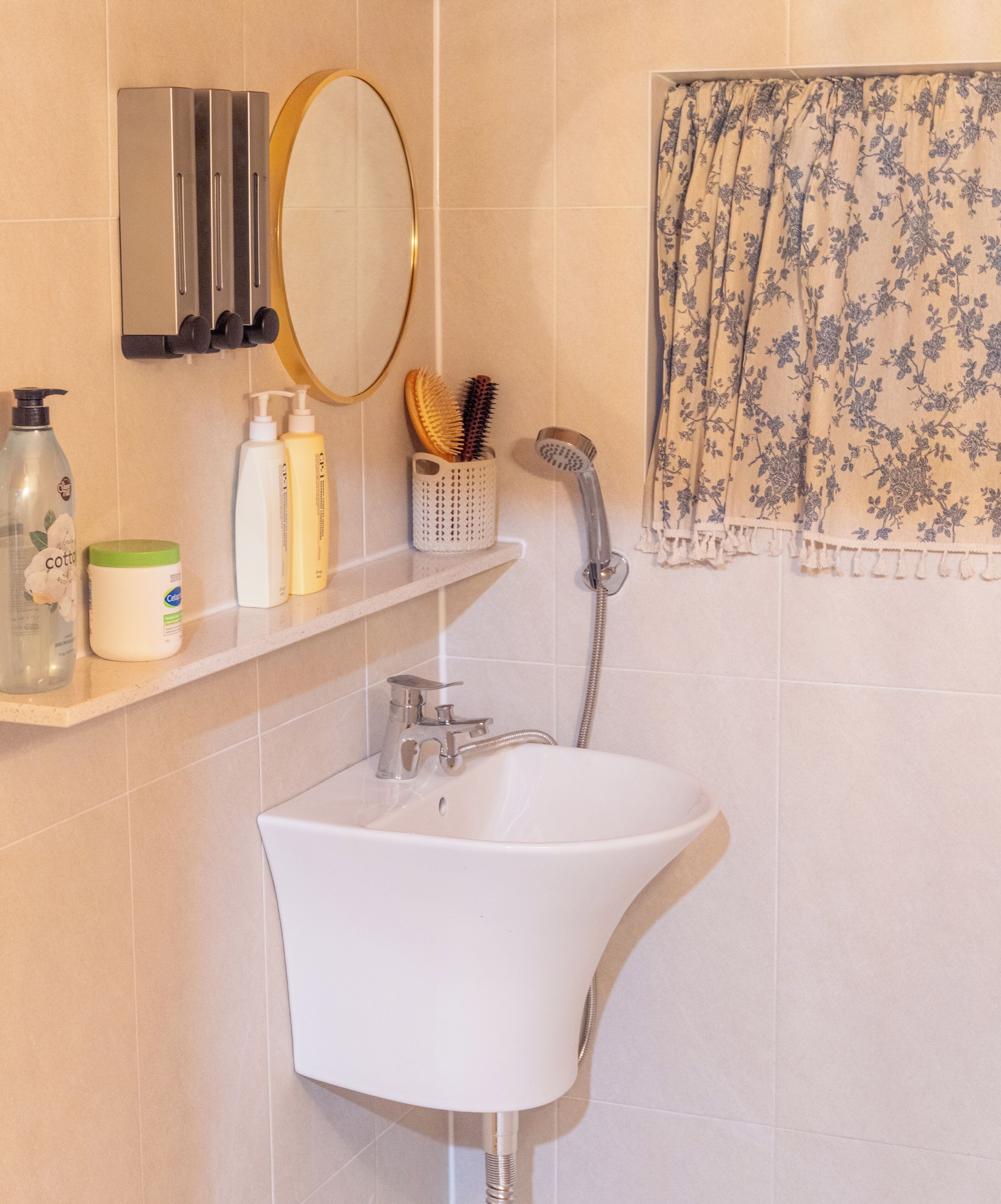 A bathroom with a white sink, a mirror, a towel rack, and toiletries on a shelf.