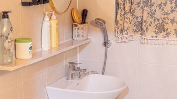 A bathroom with a white sink, a mirror, a towel rack, and toiletries on a shelf.