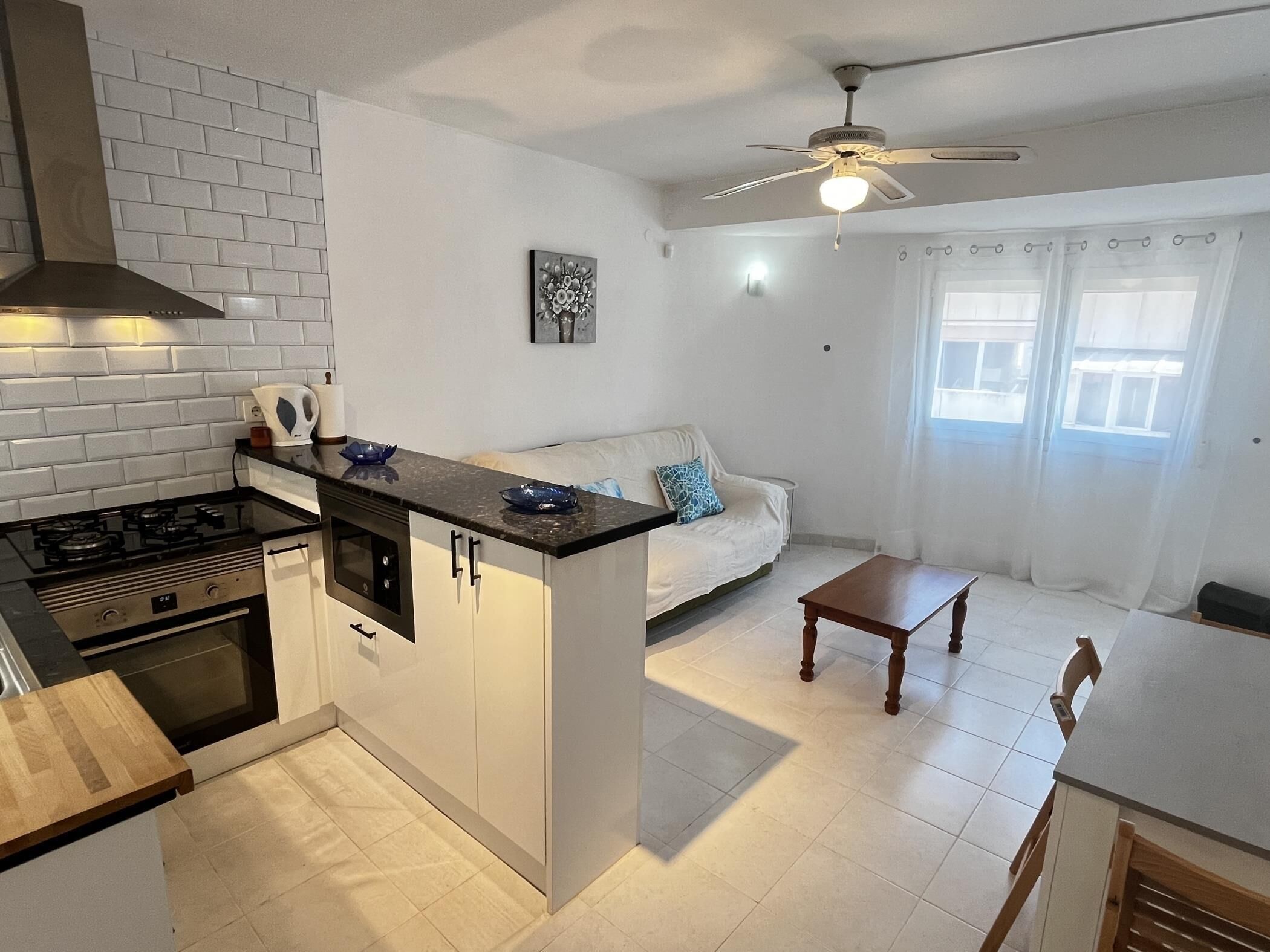 Cozinha compacta com fogão a gás, forno e pequena área de refeições com mesa e cadeiras.