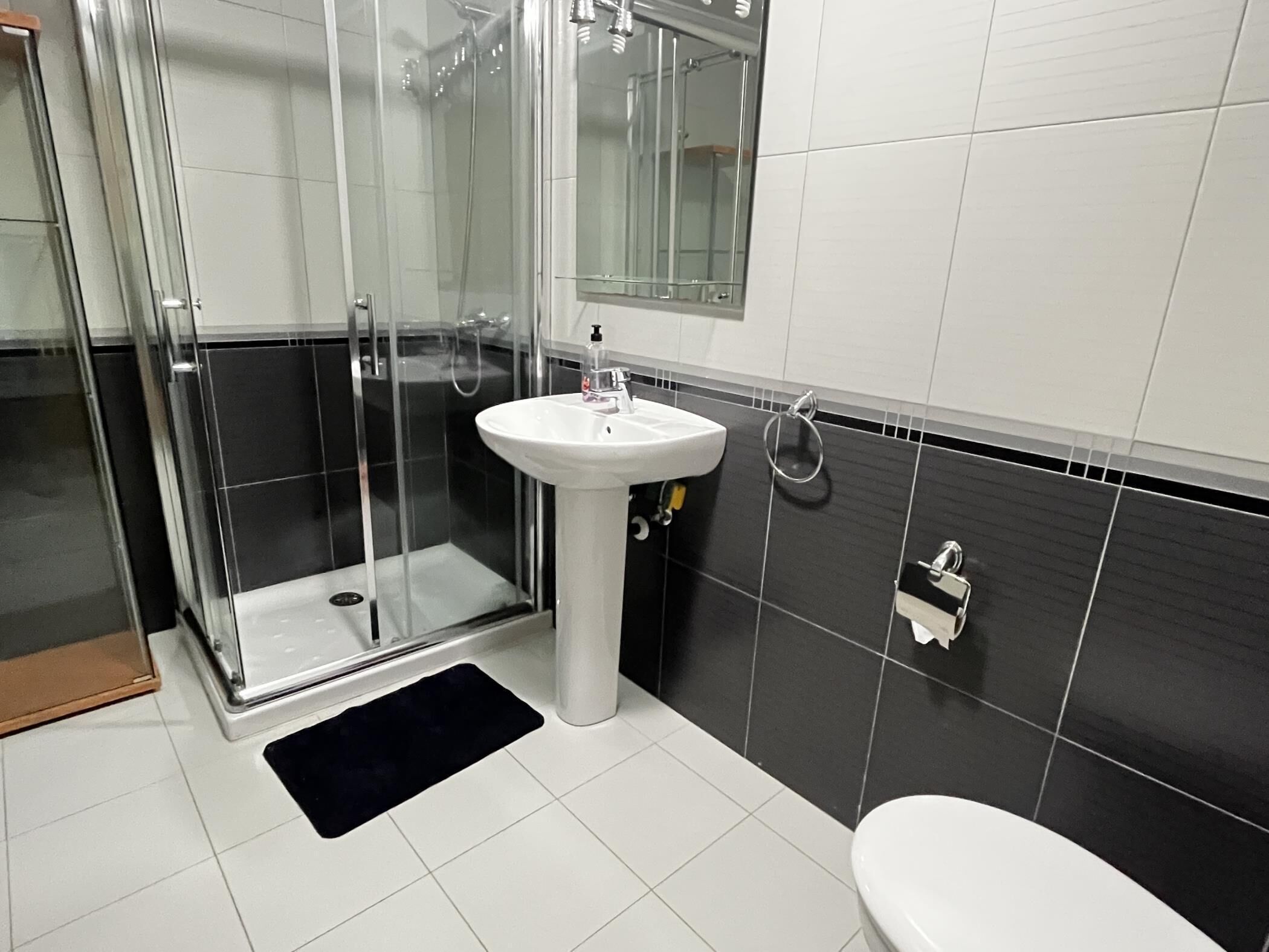 A modern bathroom with a glass-enclosed shower, a white sink, and a toilet.