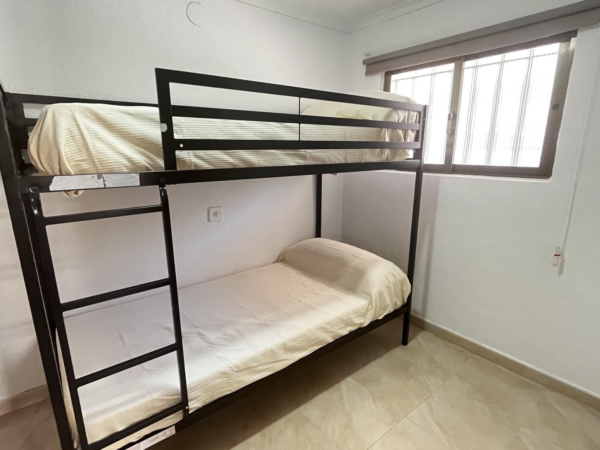 A bunk bed with a window above the lower bunk.