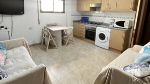 A compact kitchen with a dining table, a washing machine, and a microwave. - Ground-floor apartment in Frentemar complex for 4 people. (Calp)