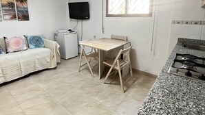 A compact living space with a kitchenette, a dining table, a sofa, and a TV mounted on the wall. - Ground-floor apartment in Frentemar complex for 4 people. (Calp)