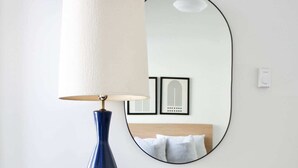 Uma cômoda de madeira com uma luminária azul e um pequeno vaso branco com plantas verdes.