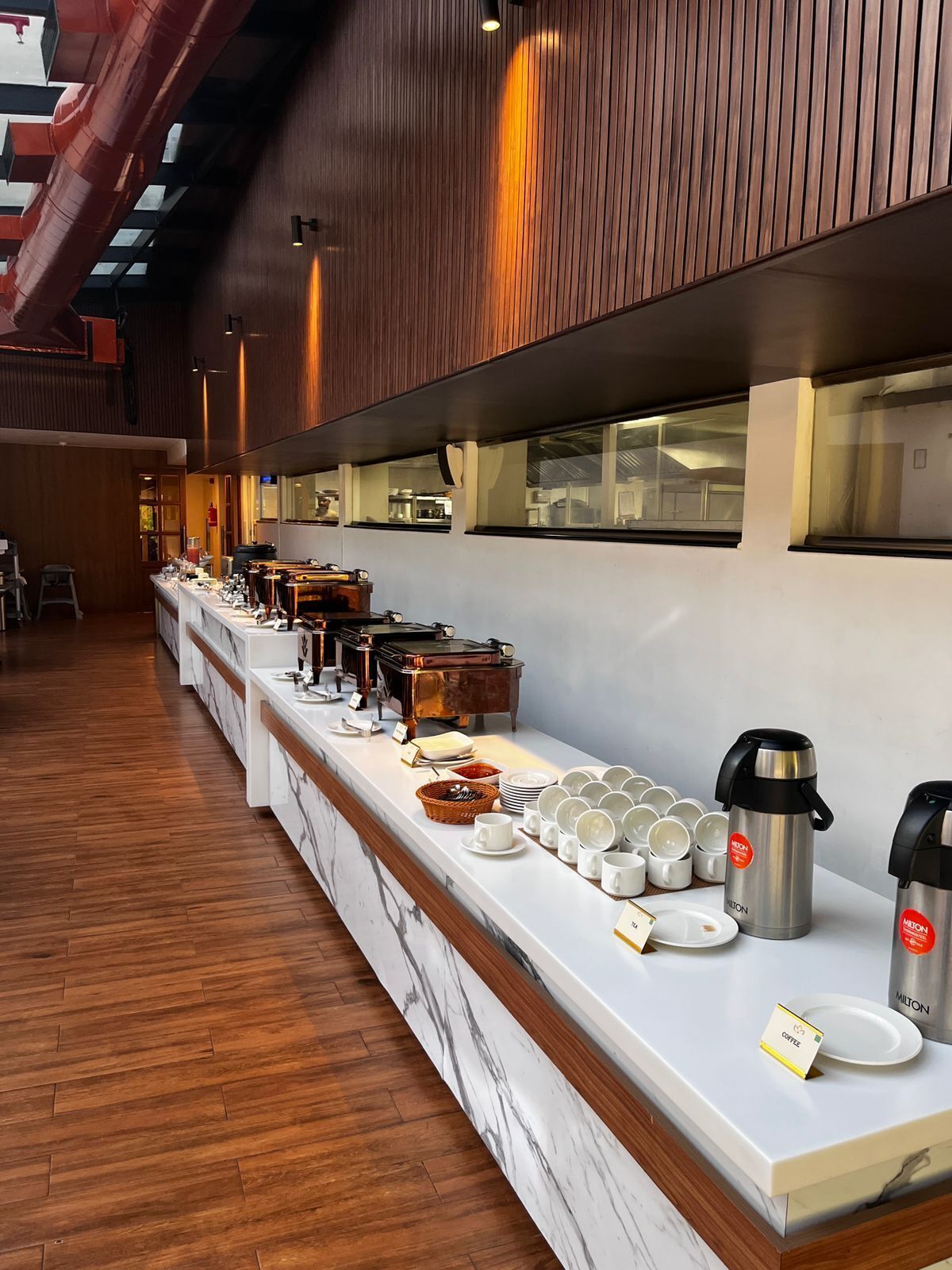 Montaje de bufé con diferentes opciones de comida y dispensadores de café.
