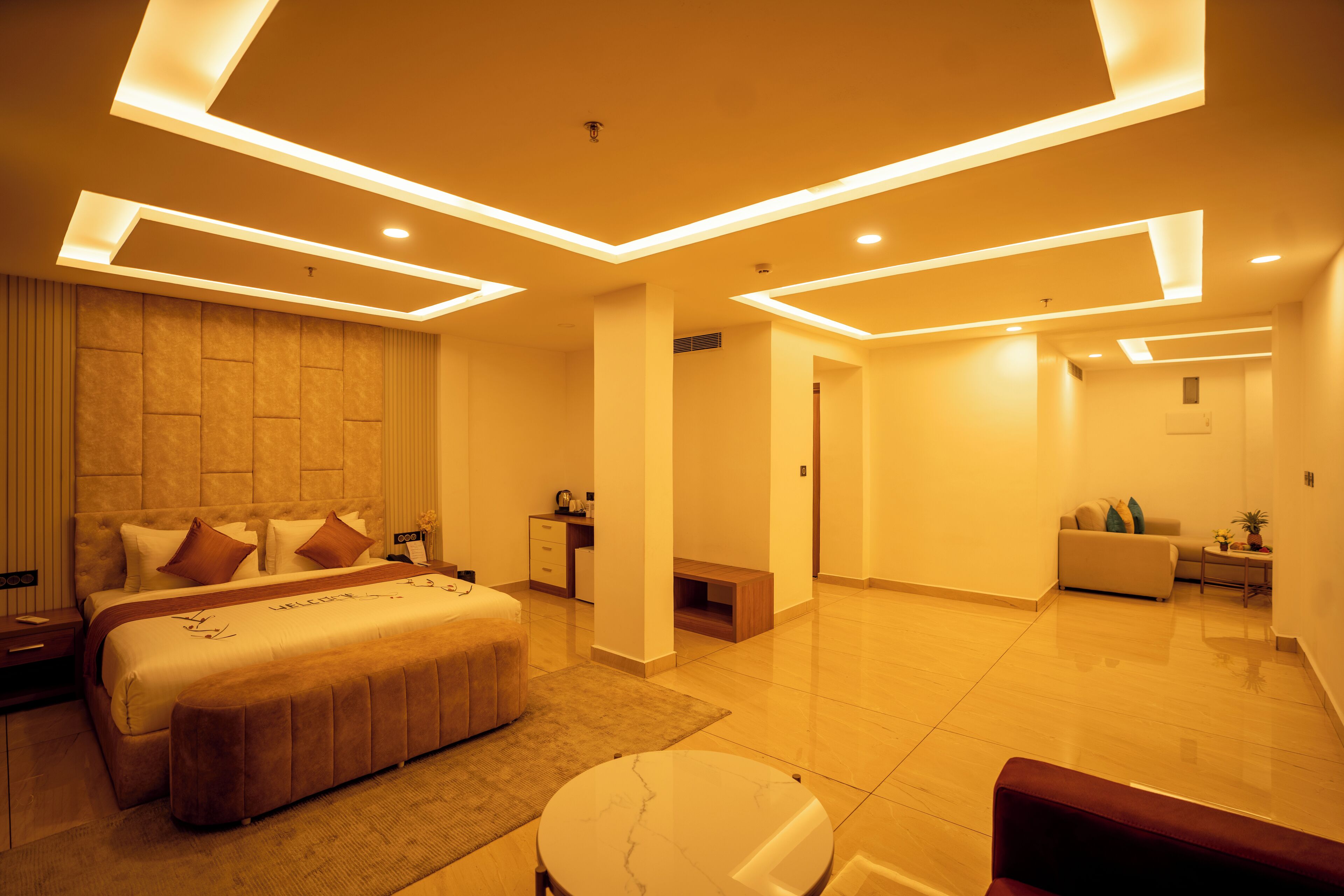 A modern hotel room with a large bed, a round table, and a sofa.