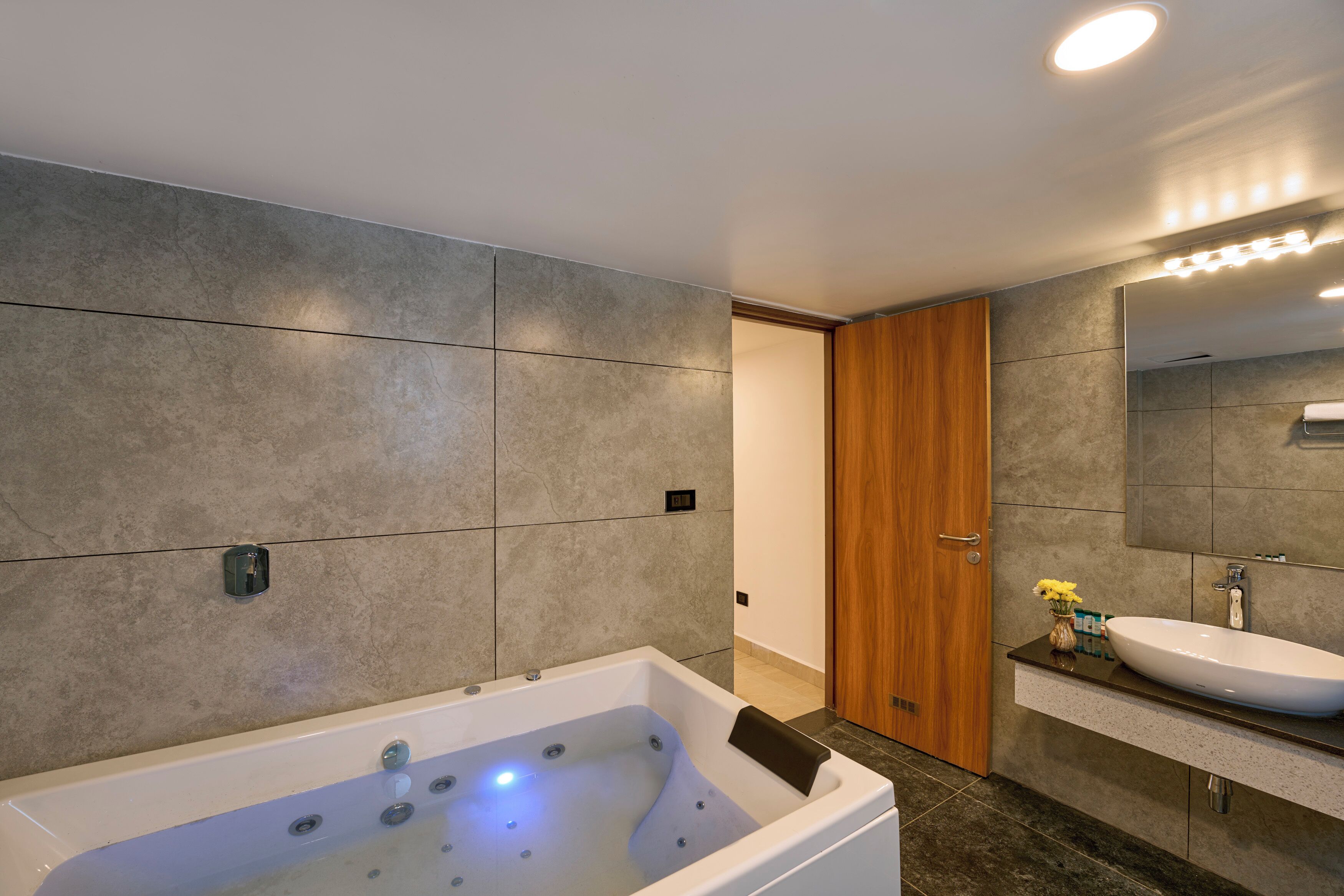 Un baño moderno con una bañera grande, una puerta de madera y un tocador con espejo.