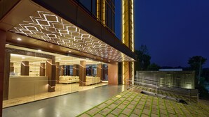A modern hotel lobby with a geometric light installation, a reception desk, and a seating area. - Serene Horizon Resort (Kumily)