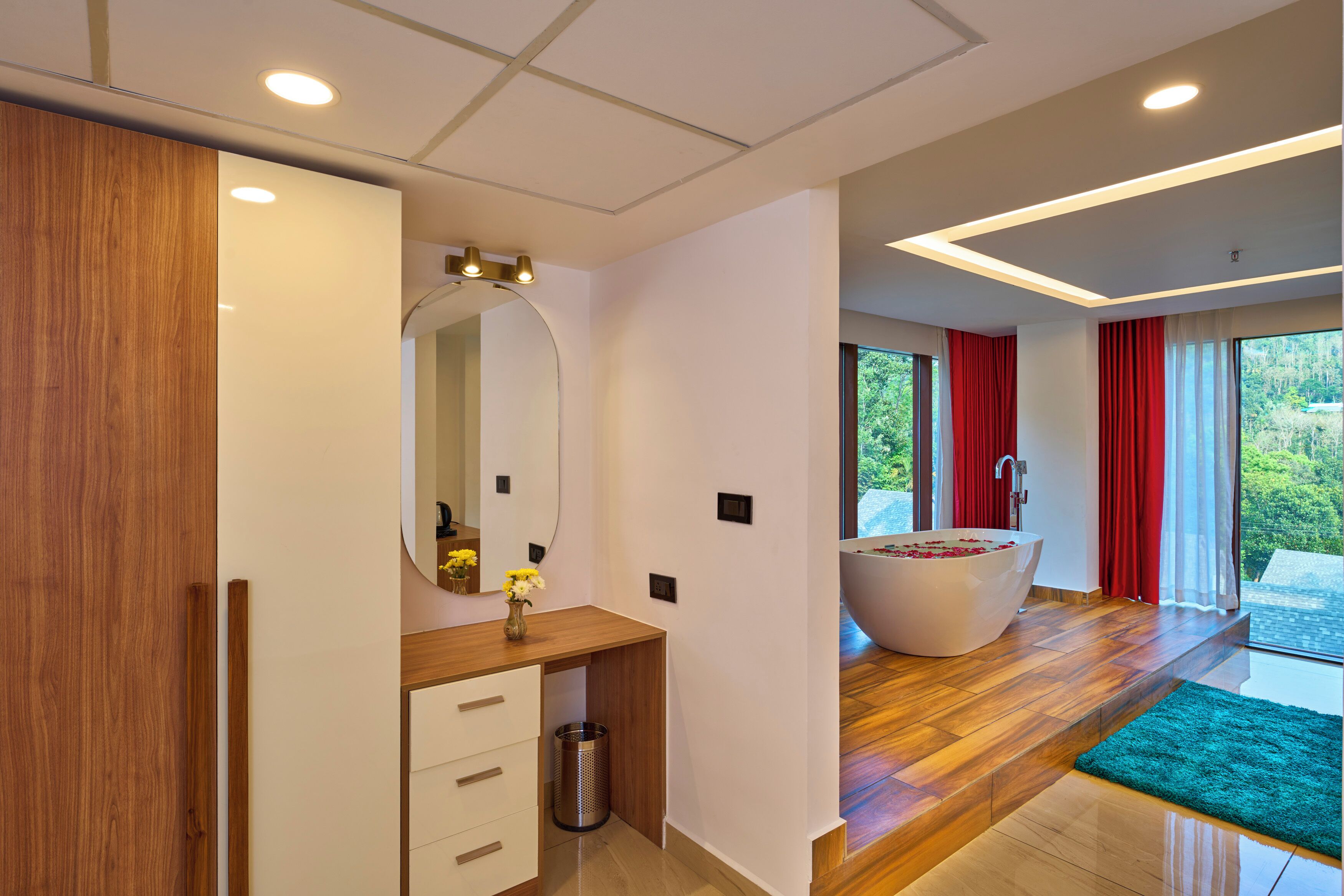 Ein modernes Badezimmer mit einer großen Badewanne, Holzboden und Blick auf Grünfläche.