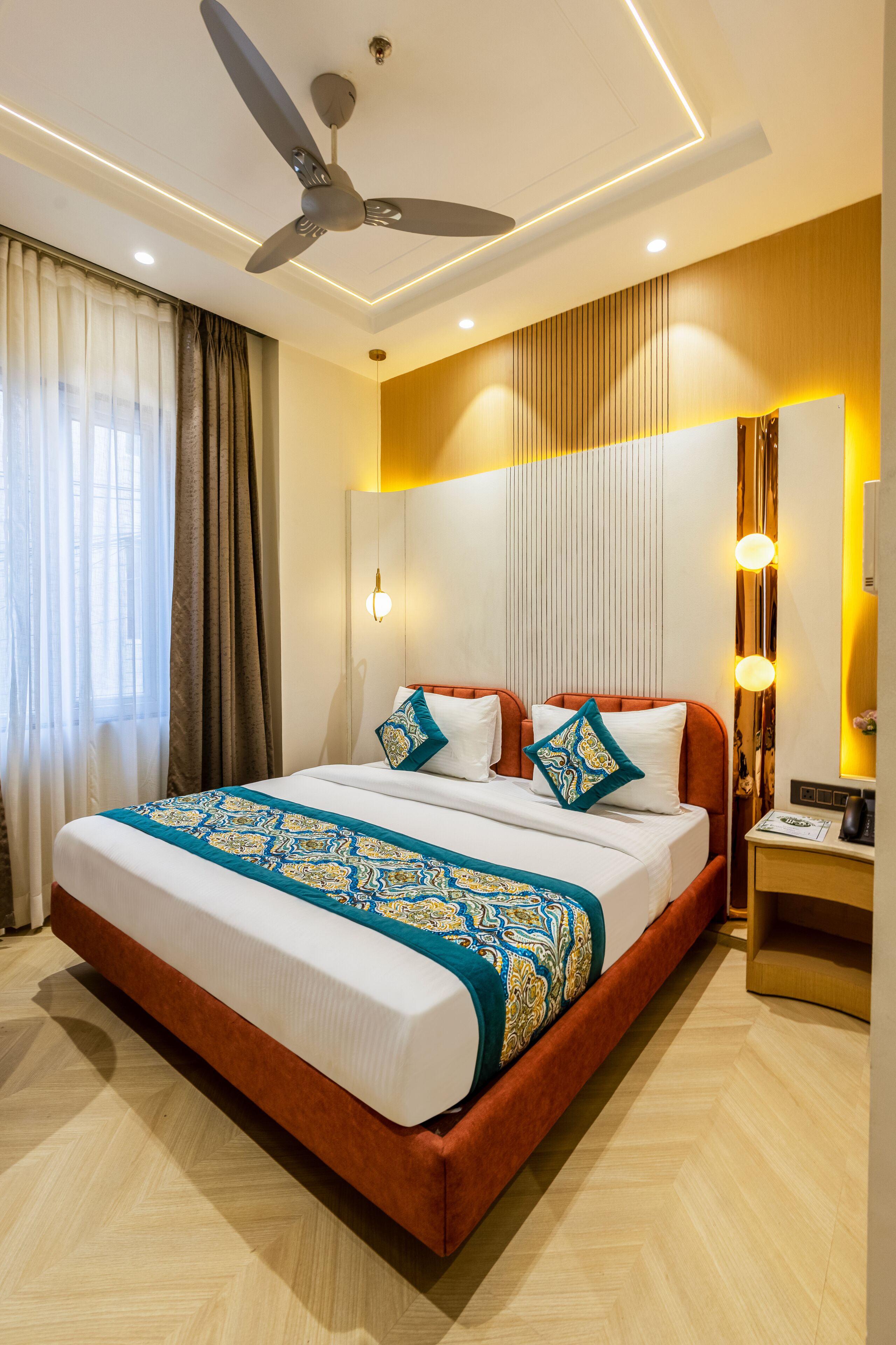 A modern hotel room with a large bed, a ceiling fan, and a nightstand with a lamp.