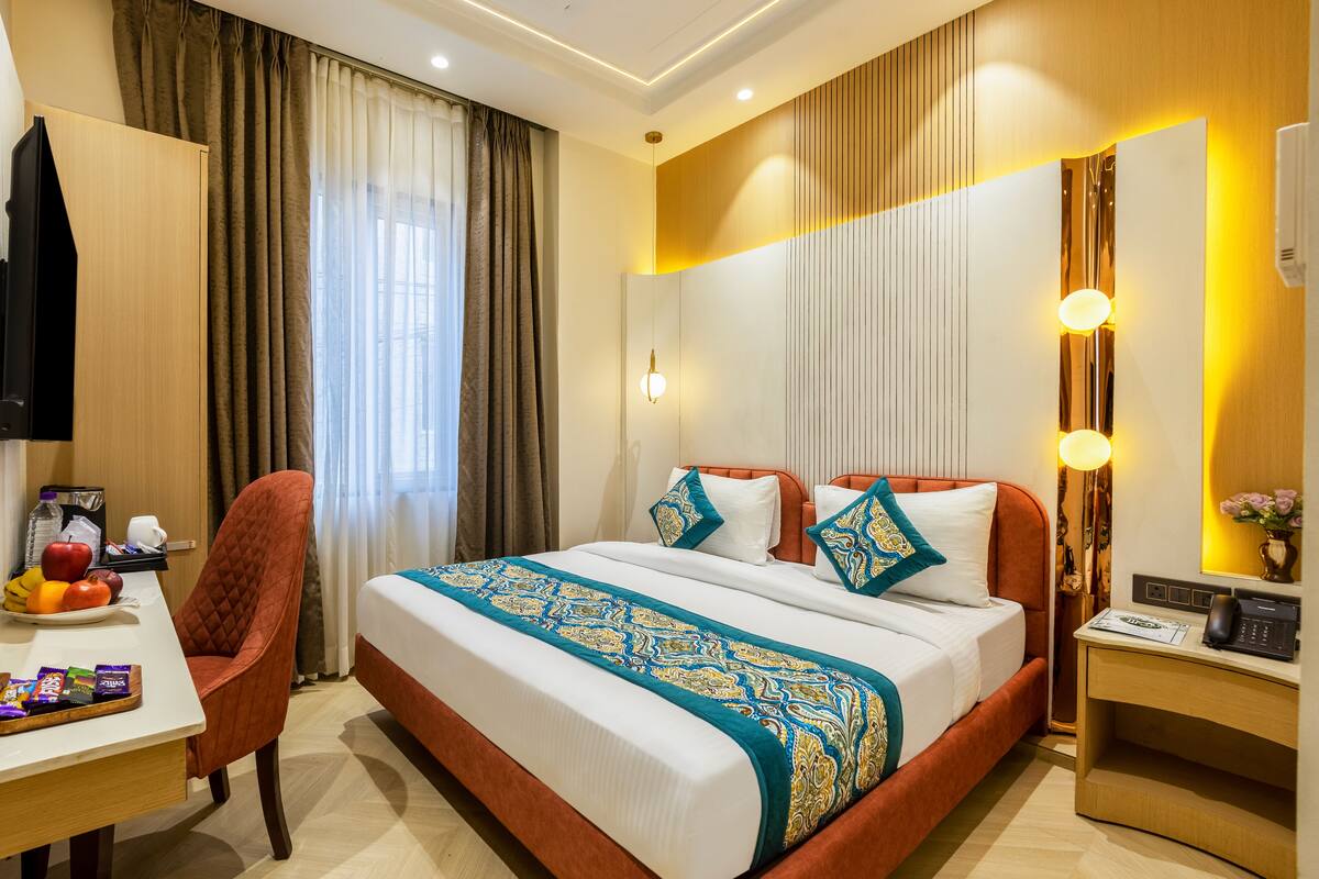 A hotel room with a bed, a desk, a chair, and a television.