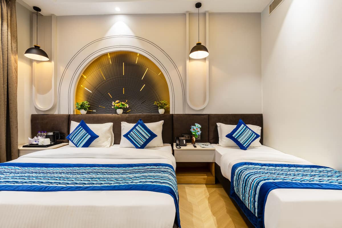 A hotel room with two beds, a large arched window, and modern lighting fixtures.