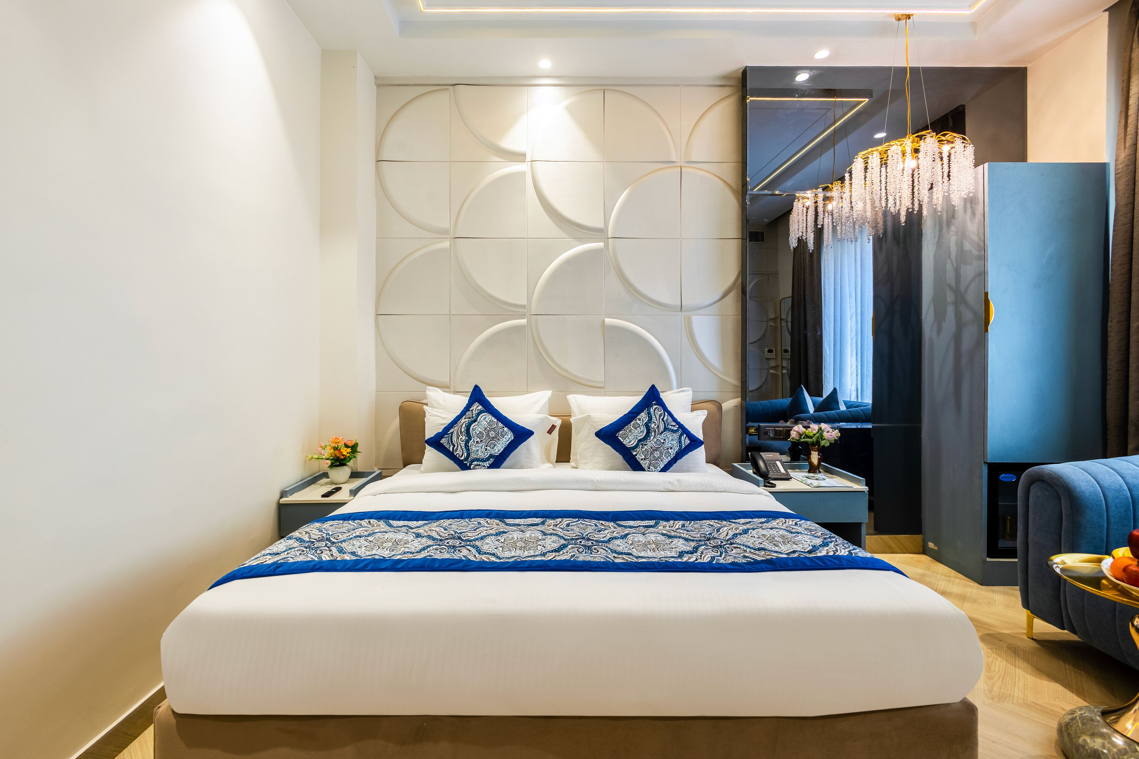 A modern hotel room with a large bed, a nightstand, a desk, and a seating area.