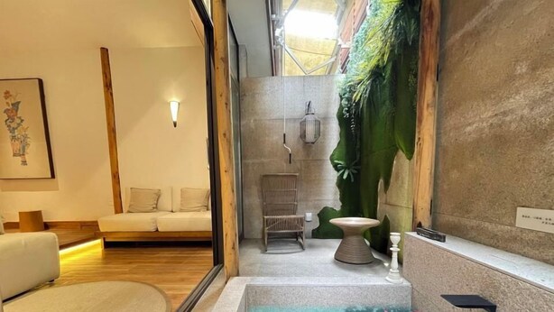 A modern bathroom with a large mirror, a bathtub with a floral design, a wooden bench, and a wall-mounted light fixture. - Ancient Charm Inn Chengdu (Chengdu)