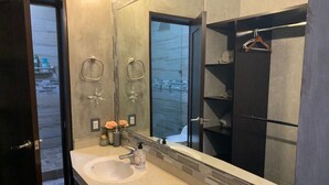 A bathroom with a large mirror, a sink, and a shower area.