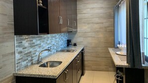 A modern kitchen with granite countertops, stainless steel sinks, and dark wooden cabinets.