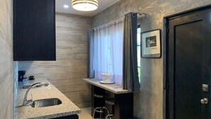 A modern kitchen with a granite countertop, stainless steel sink, and bar stools.