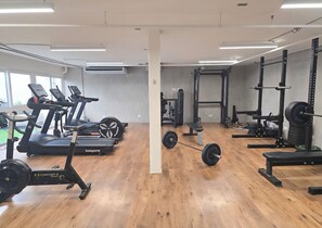 Ein Fitnessraum mit Laufbändern, einer Hantelbank und Gewichte.
