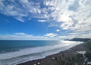 Ein Strand mit blauem Himmel, ruhiger See und einem entfernten Berg.