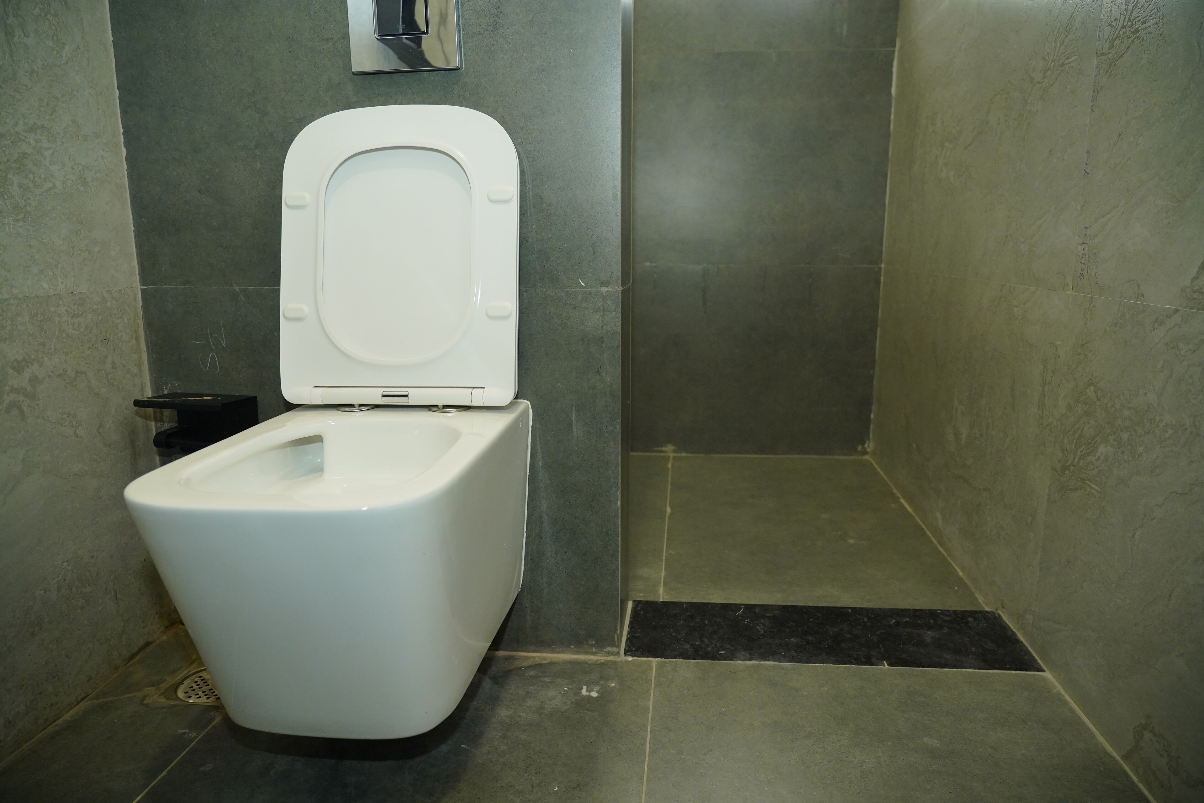 Un baño moderno con inodoro blanco, un pequeño cubo de basura y zona de ducha.
