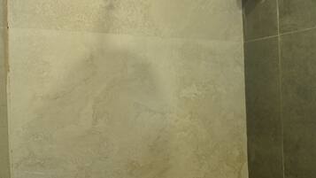 A shower with a handheld showerhead and a wall-mounted faucet.