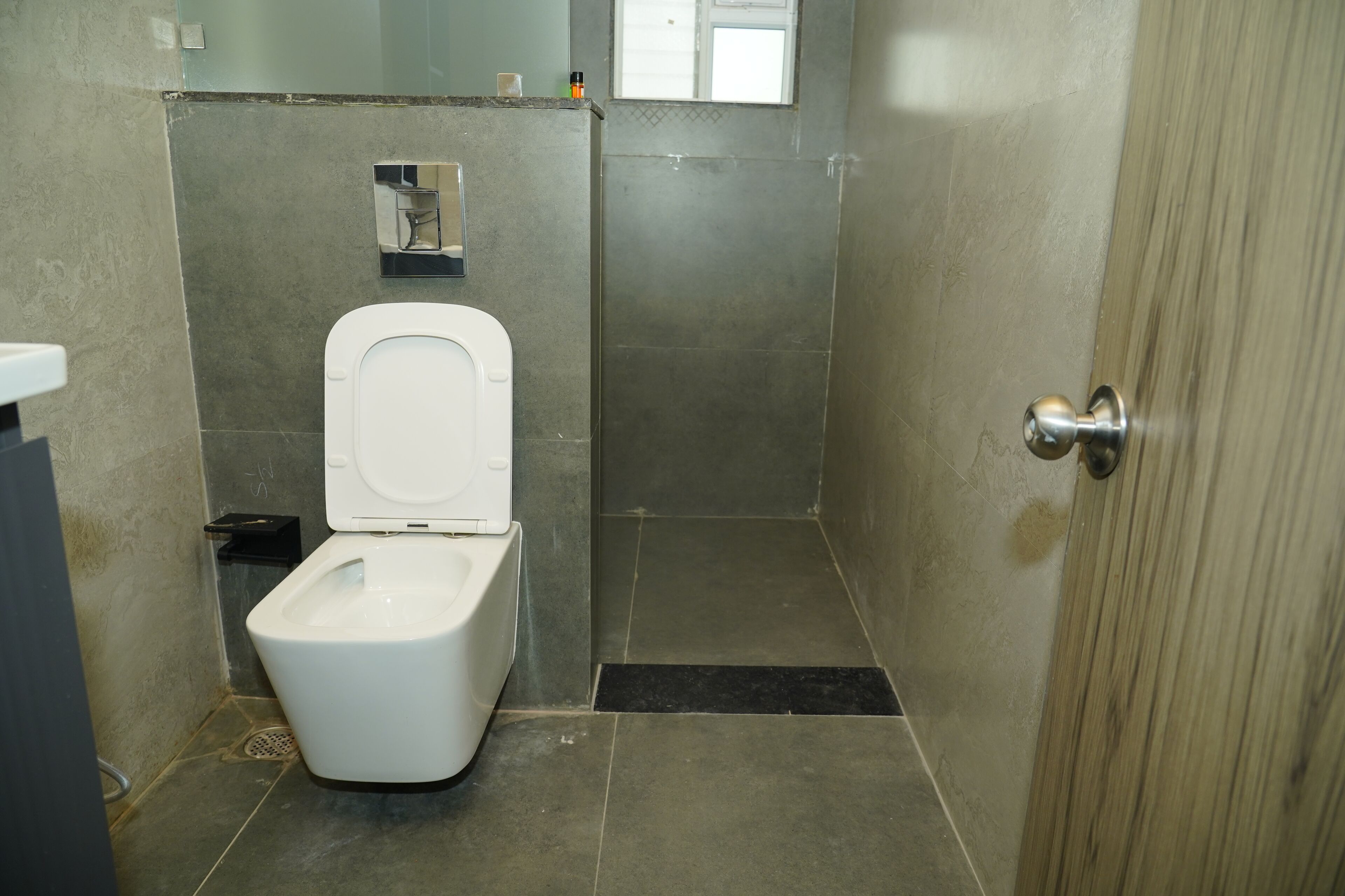 A small, modern bathroom with a toilet, a sink, and a shower area.