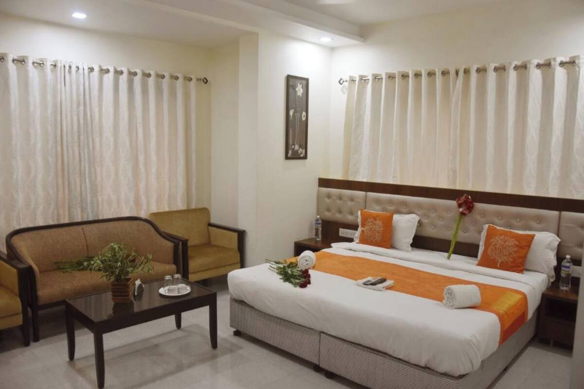 Ein Hotelzimmer mit Bett, Sofa, Couchtisch und Vorhängen.
