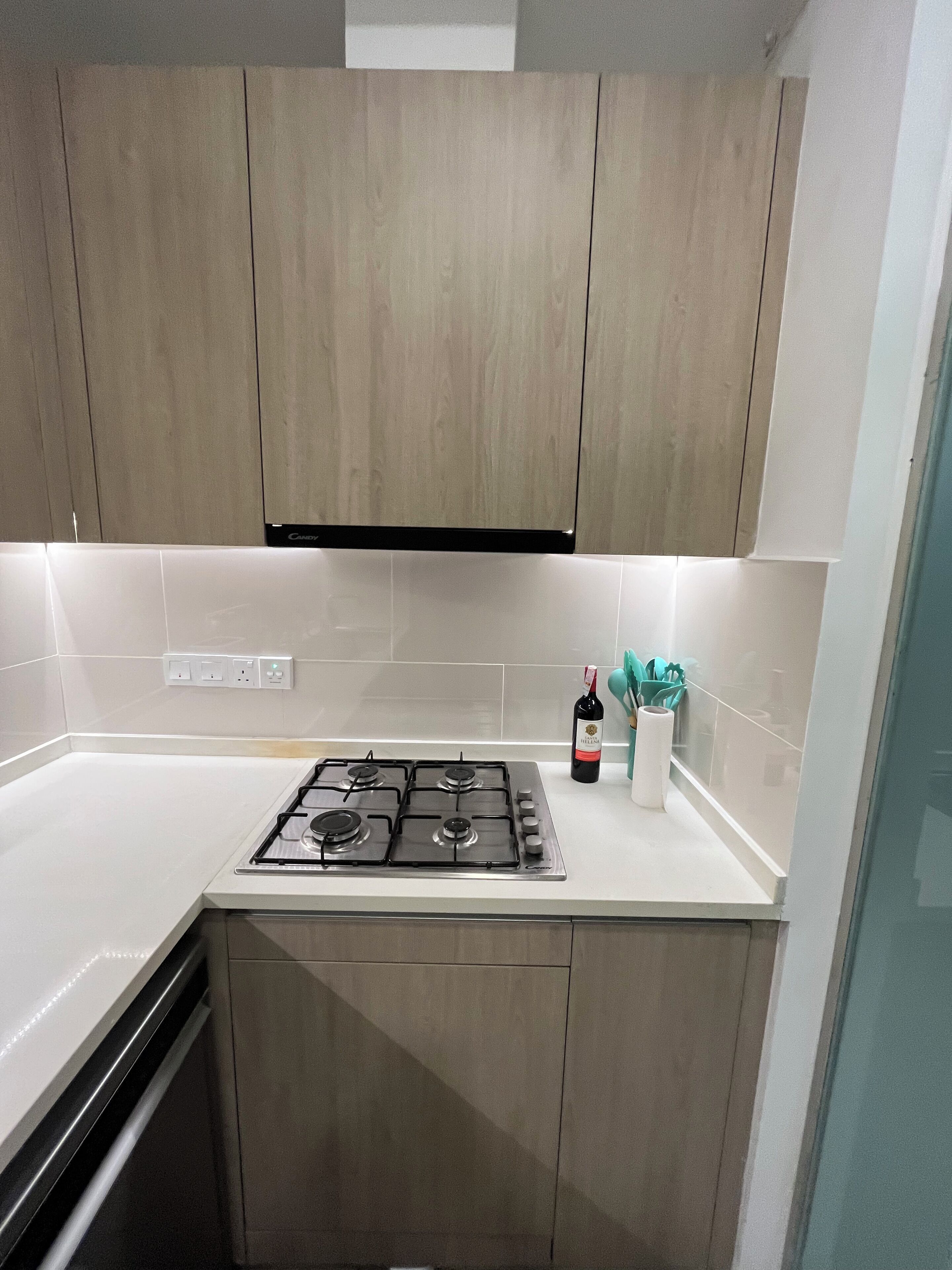 A kitchen with a gas stove, wooden cabinets, and a white countertop.